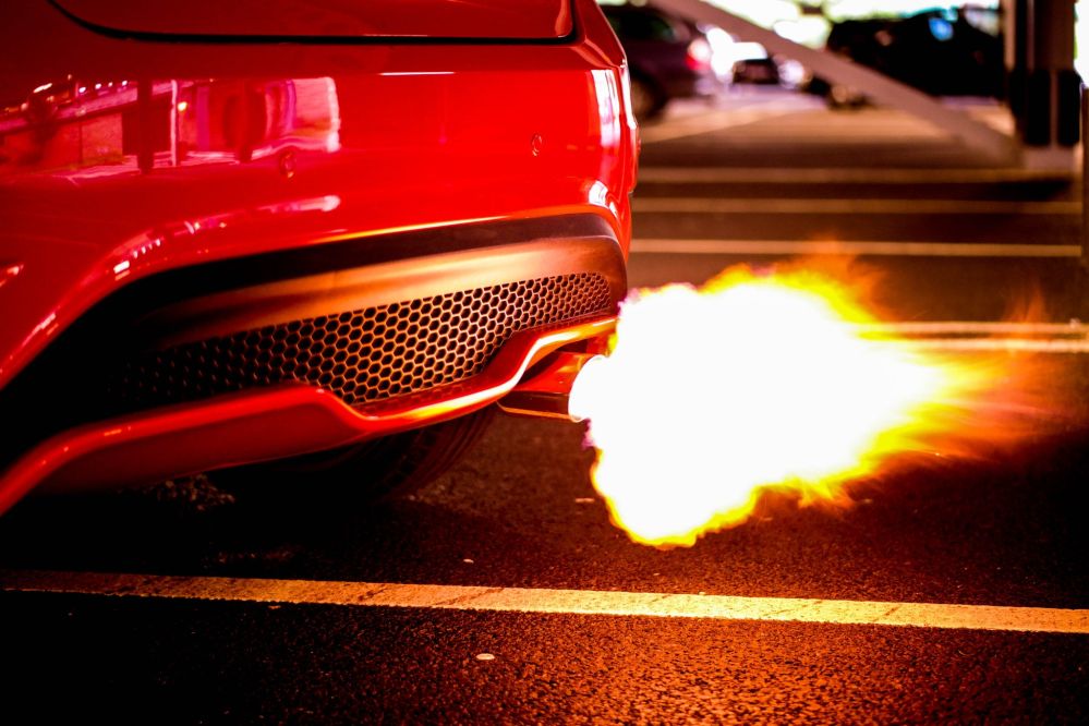 Feuer kommt aus dem Auspuff eines roten Flitzers