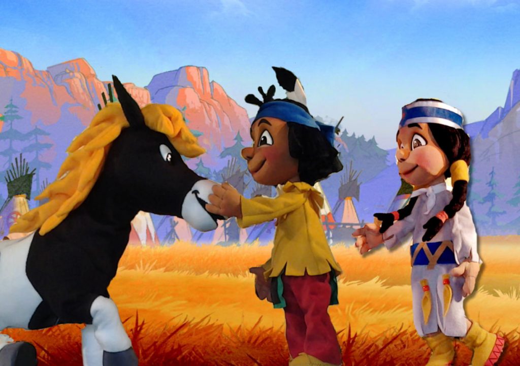 Yakari, seine Freundin und sein Pony vor gezeichneter Kulisse. Holzpuppen.