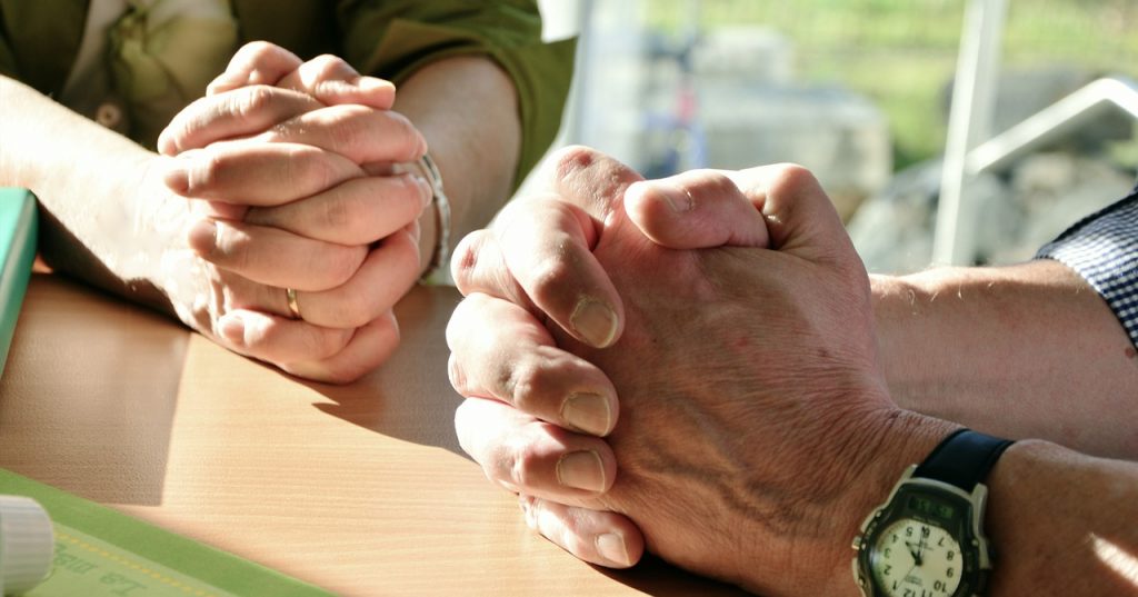 2 Menschen (Mann und Frau) beten miteinander. Man sieht nur die Hände.