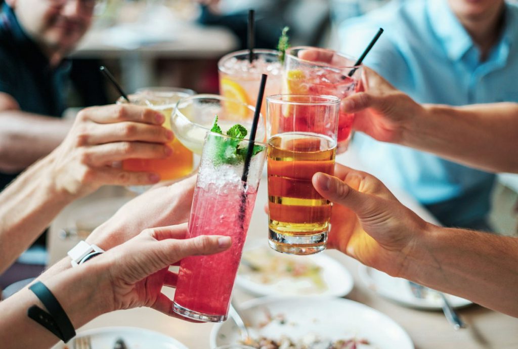 Hände halten Cocktailgläser in die Bildmitte