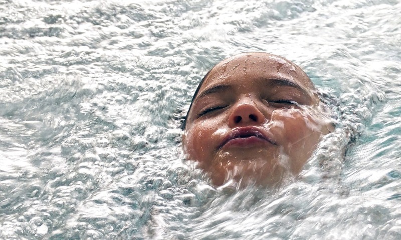 Ein Kind schwimmt auf dem Rücken liegend. Nur das Gesicht ist zu sehen.