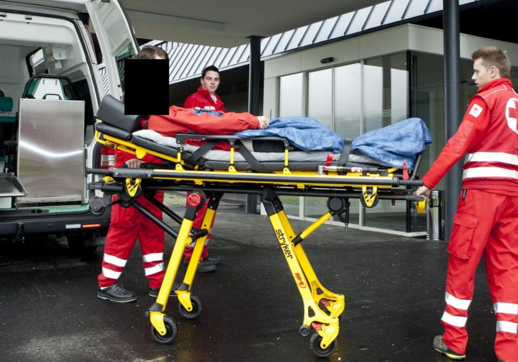 Verletzer auf Trage und Sanitäter vor Klinikum