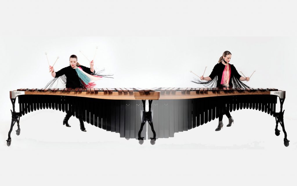 Zwei junge Frauen, präsentieren an einem großen Xylophon gleichzeitig ihre musikalischen Fertigkeiten.