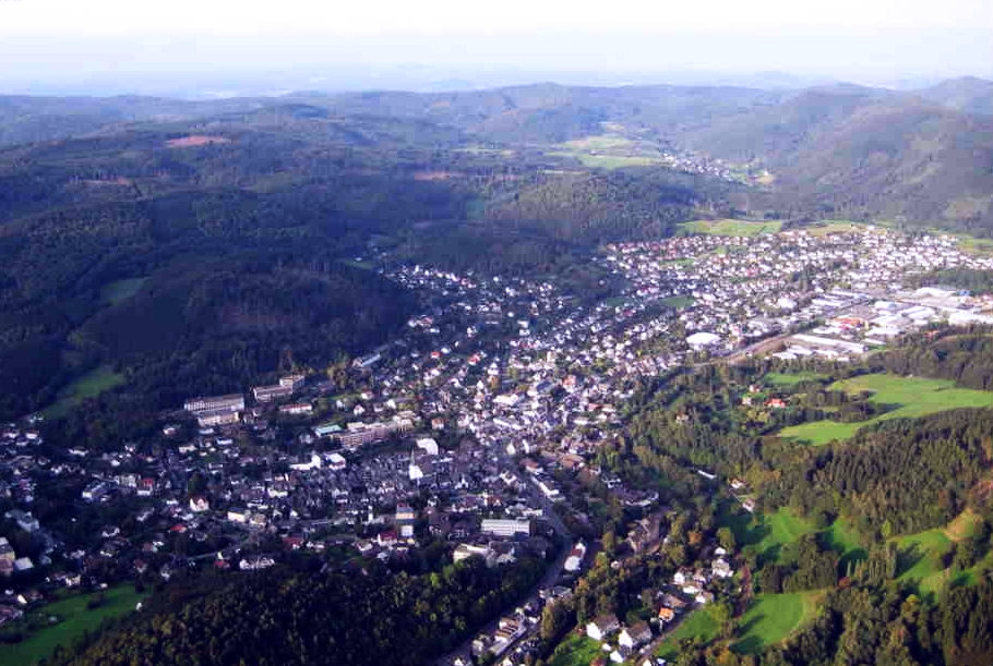 Luftaufnahme von Bad Laasphe. Die Stadt von oben, gesäumt von mittelgebirgigen Anhöhen und Wald.