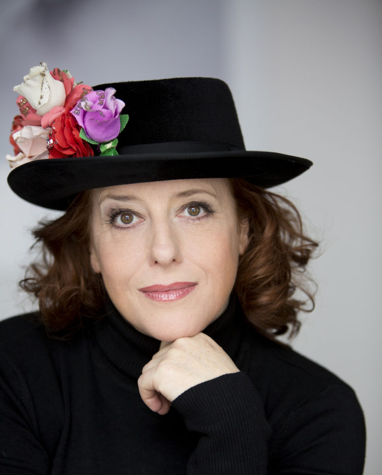 Die aus dem Fernsehen bekannte Kabarettistin Luise Kinseher ist auf diesem Porträtfoto zu sehen - mit blumendekoriertem Hut und schwarzem Pulli. 