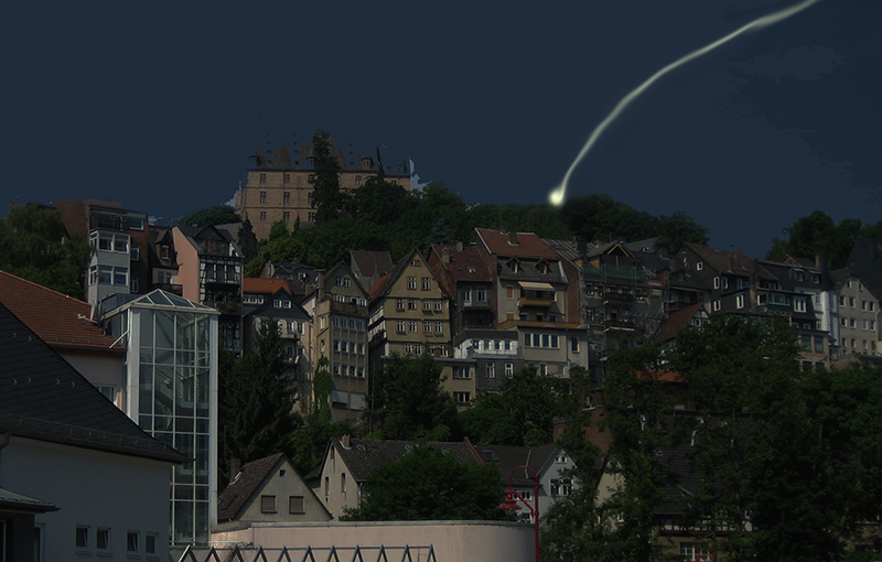 Marburg bei Nacht. Oben das Schloss, darunter Häuser. Ein Lichtpunkt mit Lichtspur ist am Himmel zu sehen.