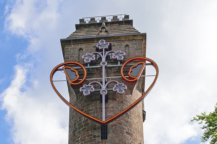 Der Spiegelslustturm (oberes Drittel mit Herz) bei Tageslicht vor bewölktem Himmel.