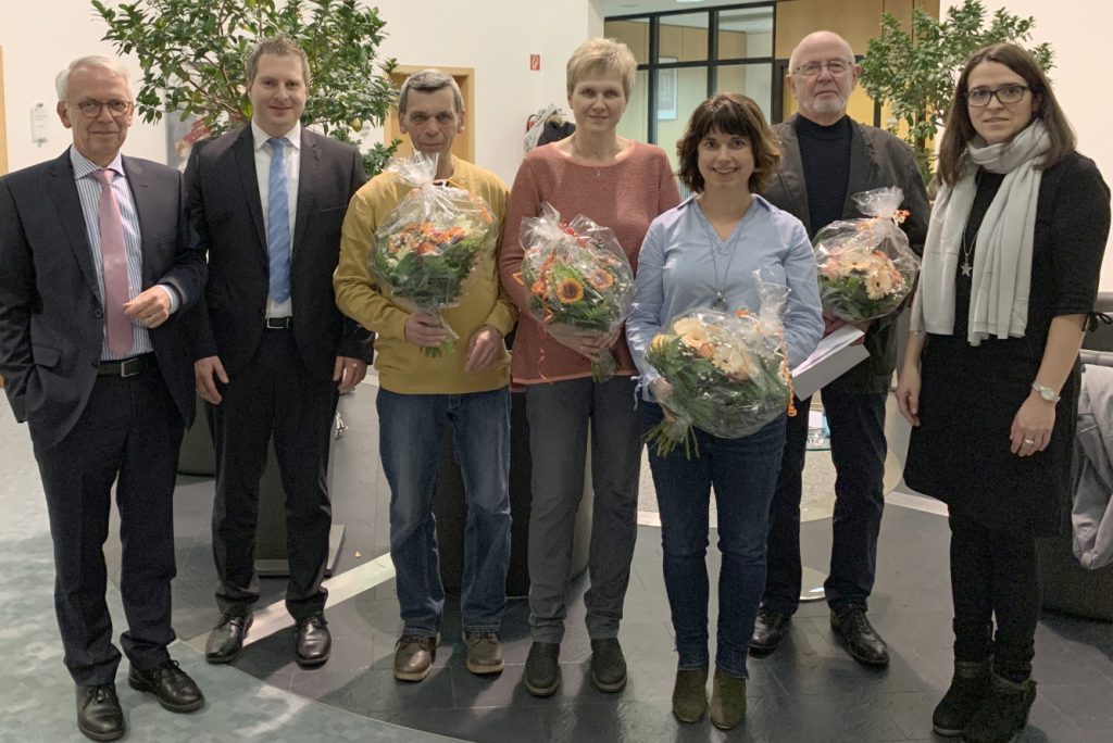 Die Gewinnerinnen und Gewinner mit jeweils einem Blumenstrauß stellen sich zum Gruppenfoto mit den Bankangestellten.