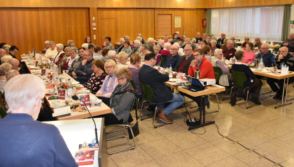 Knapp 80 ältere Damen und Herren sitzen an gedeckten Kaffeetischen im Dorfgemeinschaftshaus.