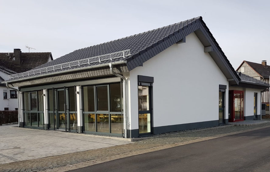 Dorftreff von der Rückseite. Große Fensterfront. Bodentief. Parkplatz davor.