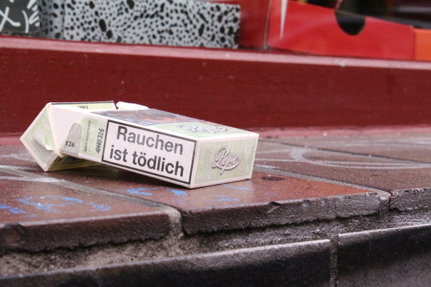 Eine angebrochene Zigarettenschachtel liegt verlassen auf einer Außenfensterbank. Die Aufschrift auf der Banderole: "Rauchen ist tödlich".