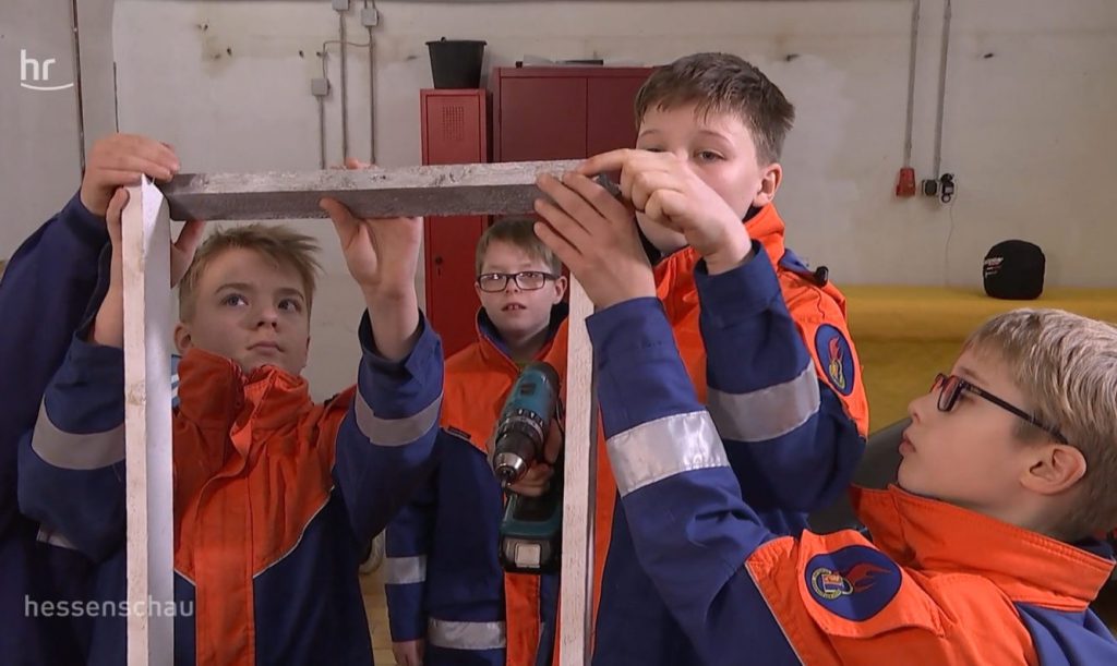 Vier Jungen aus der Jugendfeuerwehr Weifenbach bauen eine Seifenkiste zusammen. Sie tragen Jugendfeuerwehr-Uniformen.