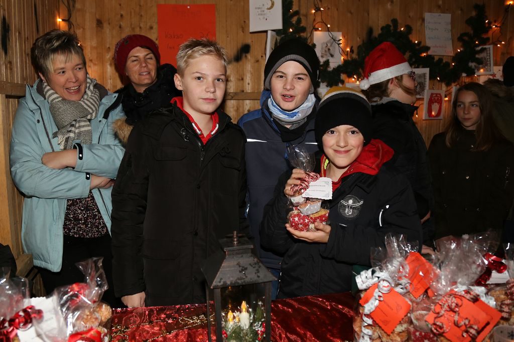Schüler an einem Stand des Weihnachtsmarkts. Sie bieten Lose für die Tombola an.