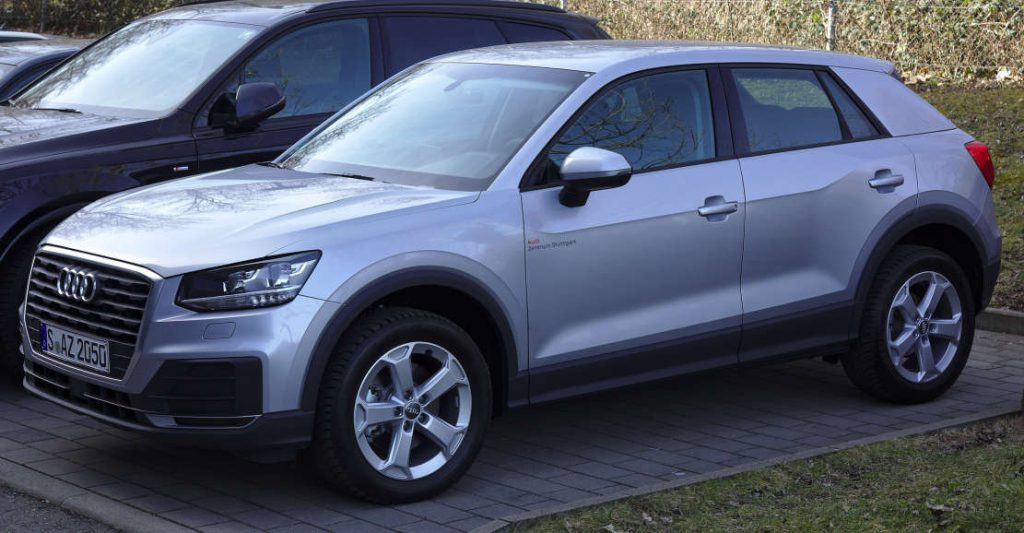 Ein Audi Q2 in Grau mit Alufelgen auf einem Parkplatz.