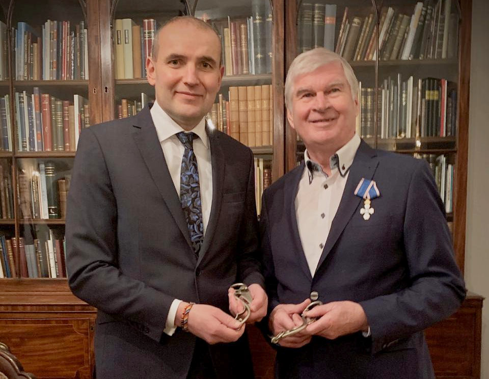 Der Träger des Falkenordens (am Revers befestigt) und der Präsident vor einem Bücherregal.