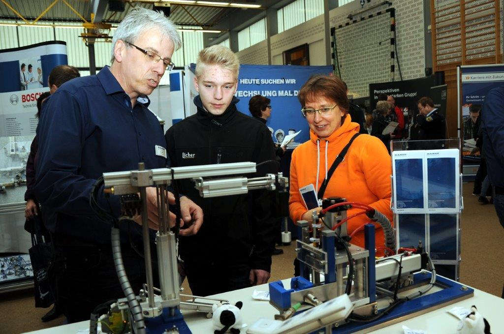 Besucher am Stand. Betrachtung einer Fertigungsmaschine.