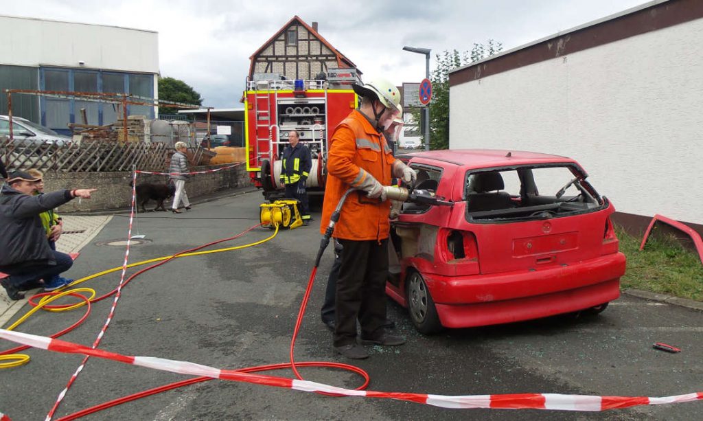 Feuerwehrmann zerschneidet einen Schrott-Pkw mit der Trennschere.