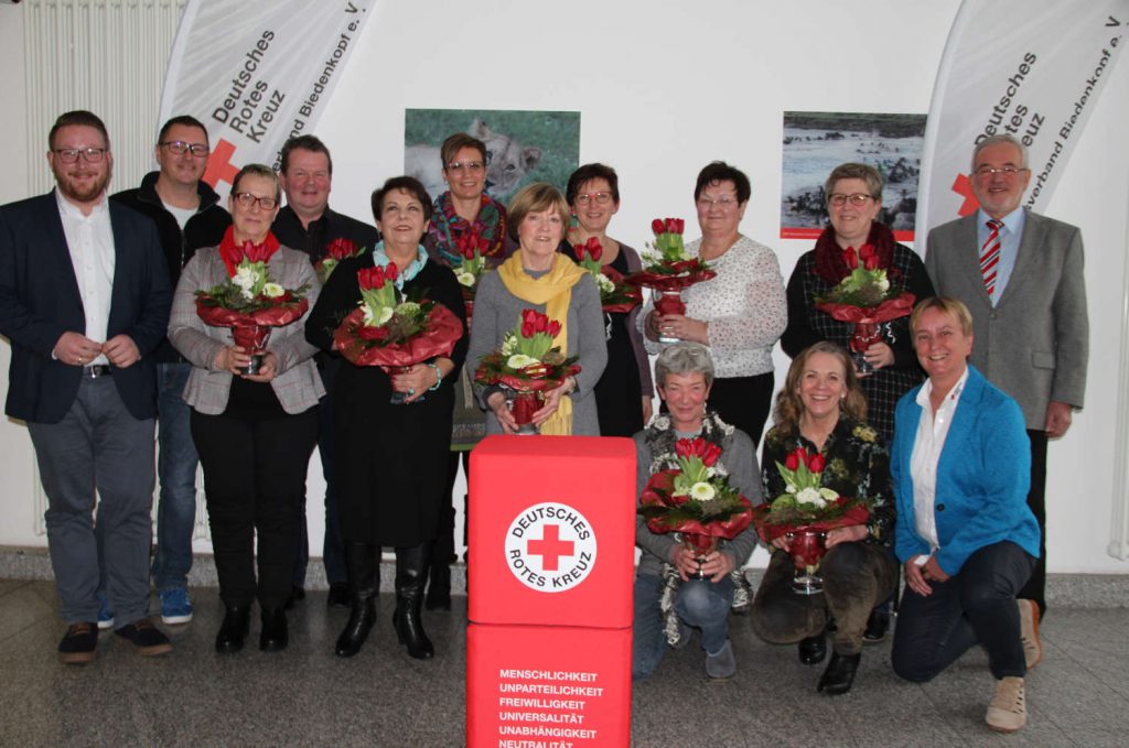 Geehrte mit Blumen und Vorstand des DRK-Kreisverbands stellen sich zum Gruppenfoto.