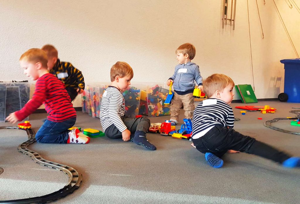 Spielende kleine Jungs mit Steckbausteinen auf einem Teppich.