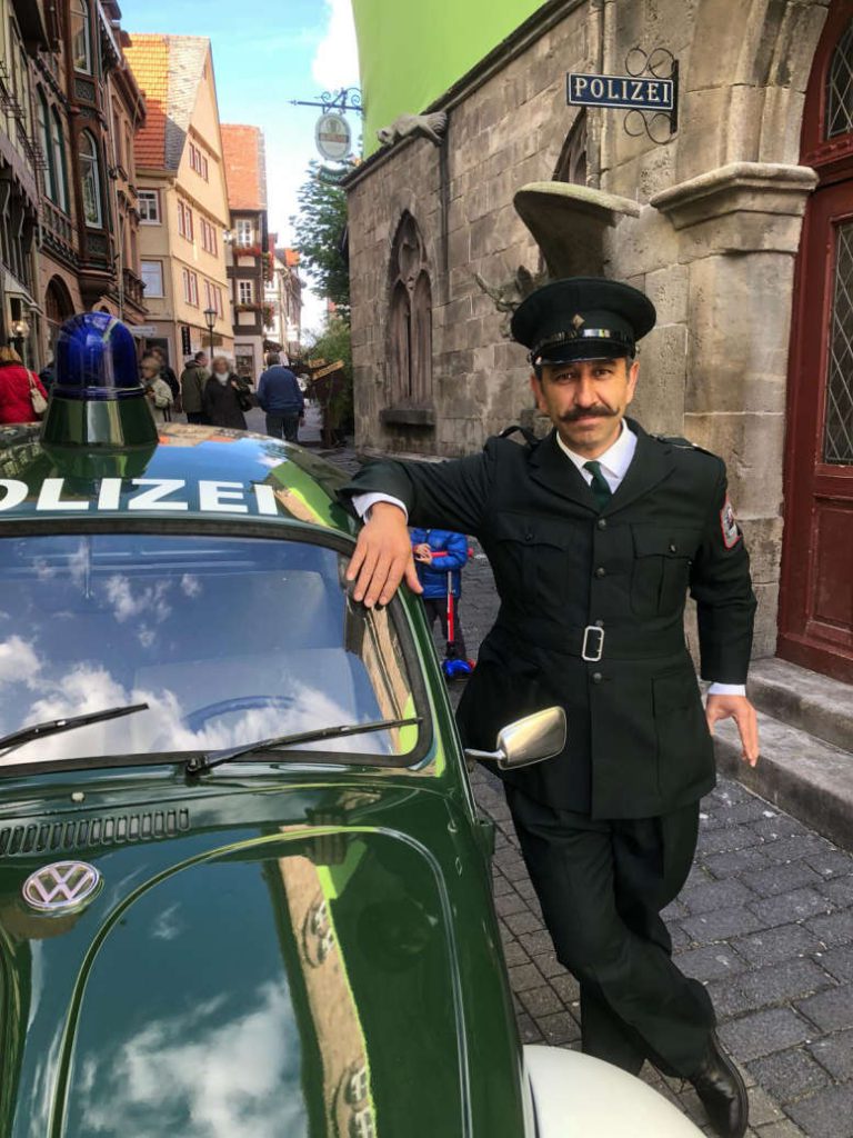 In einer Altstadtgasse ein Polizeikäfer aus den 70ern und ein Wachtmeister in historischer Uniform daneben.