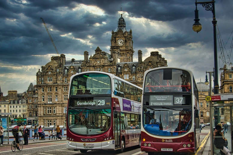 2 moderne Reisebusse vor der Kulisse von Edinburgh .