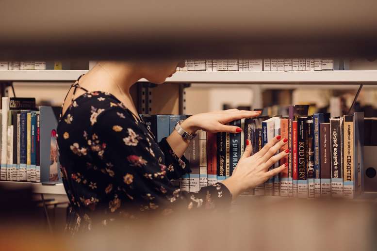 Frau in einer Bücherei zwischen Büchern