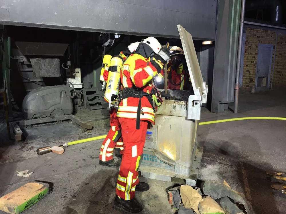 Nahaufnahme von drei Feuerwehrmännern die den Behälter löschen und verfüllen.