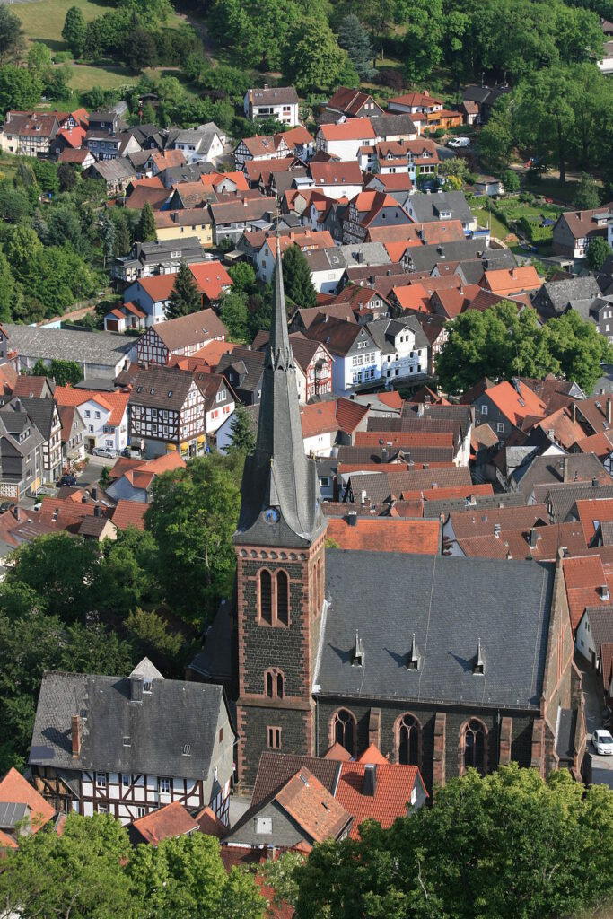 Altstadt mit Kirche und Kirchturm inmitten von Wald und Wiesen.