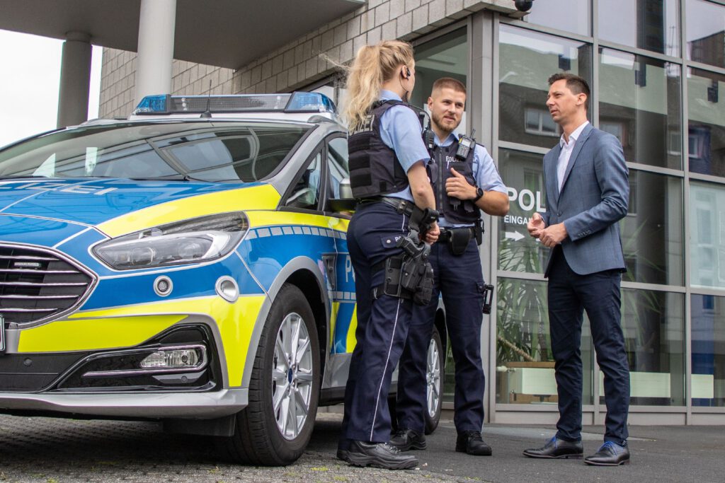 Polizeifahrzeug, 2 Beamte, Mann im Anzug