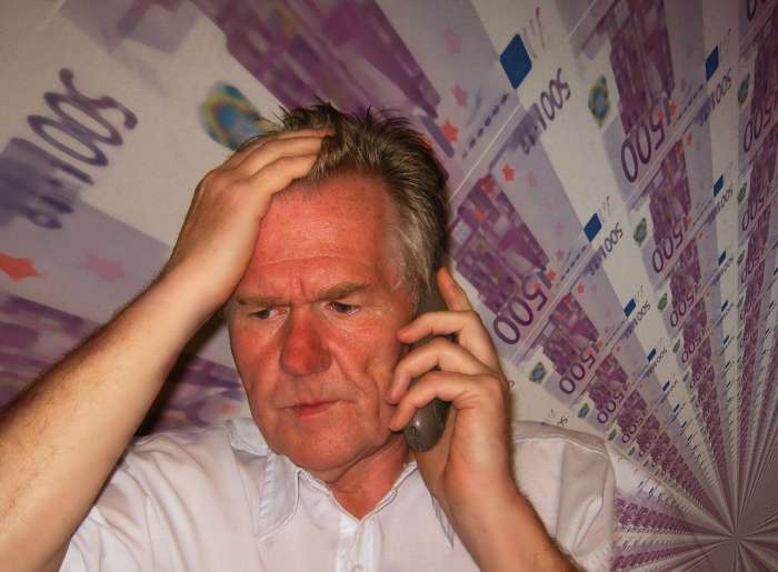 Senior telefoniert. Dahinter: Geldscheine.