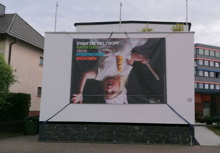 Großformatiges Poster an einer weißen Hausfassade