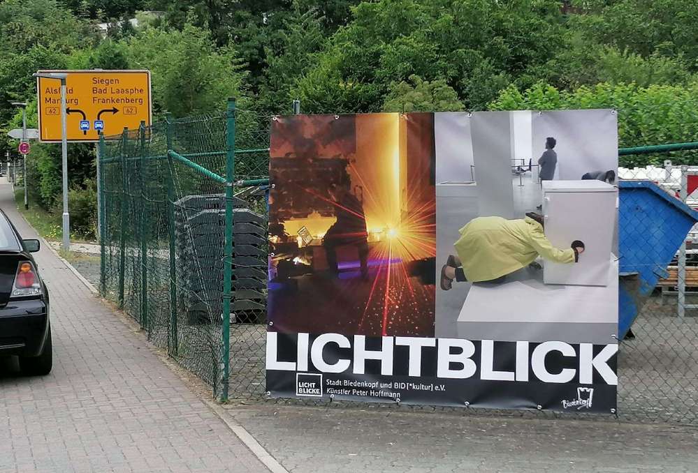 Kunstplakat an einem Maschendrahtzaun