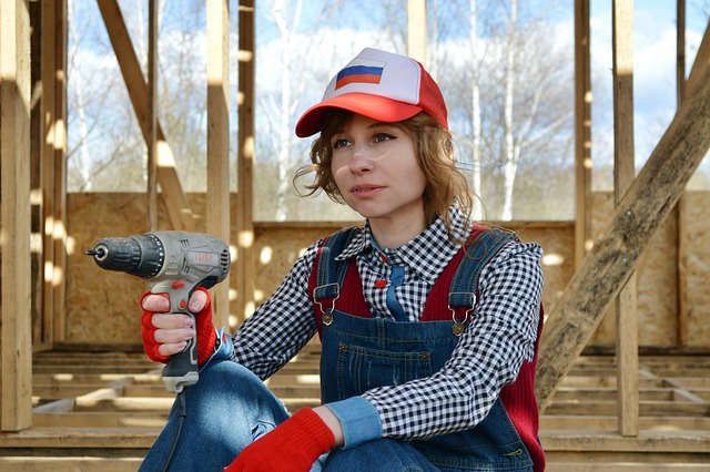 Junge Frau mit Bohrmaschine und Latzhose