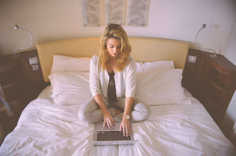 Frau auf dem Bett arbeitet am PC