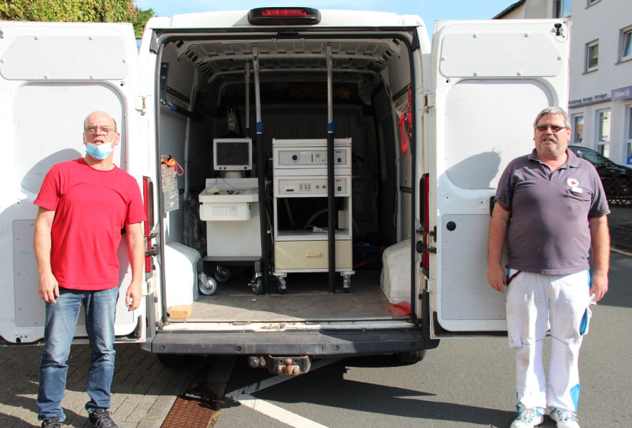 2 Männer vor geöffnetem Transporter mit Hilfsgütern
