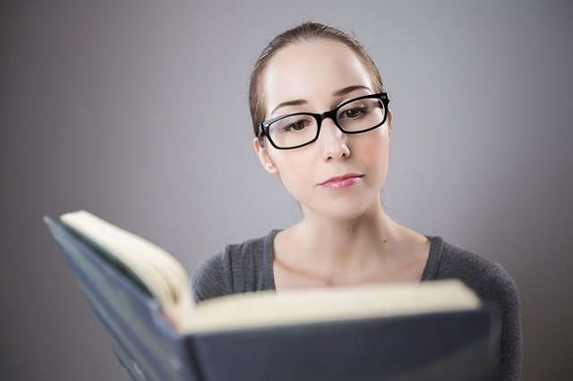 Frau mit Brille liest in einem Buch