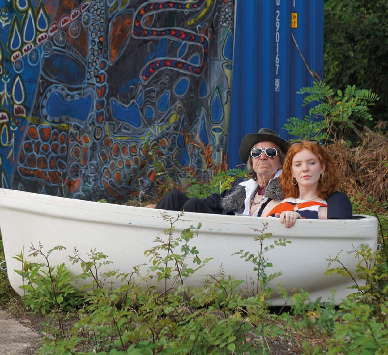 Mann und Frau (2 Darsteller) in einem Boot vor blaugemustertem Vorhang