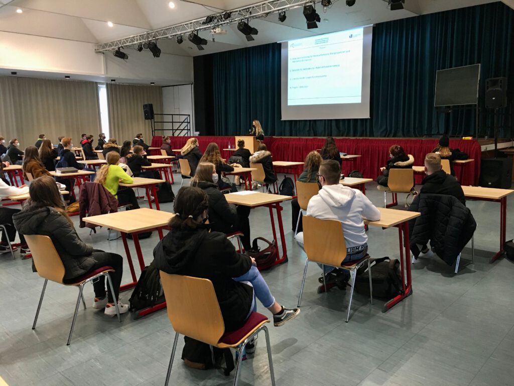Schüler an Pulten - vorn eine Fachkraft die Vortrag hält