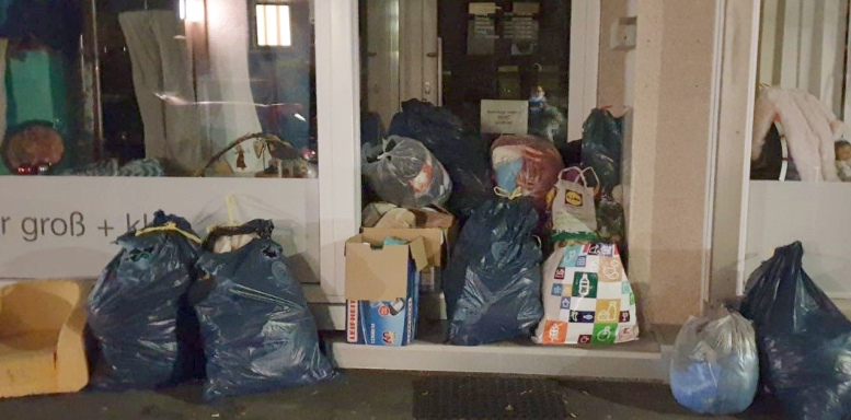 vor einem Eingang liegen haufenweise gefüllte Tüten und Säcke.
