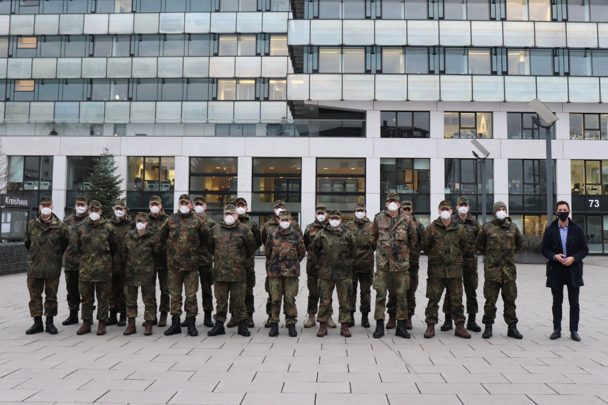 20 Soldatinnen und Soldaten mit Landrat vor hohem Gebäude