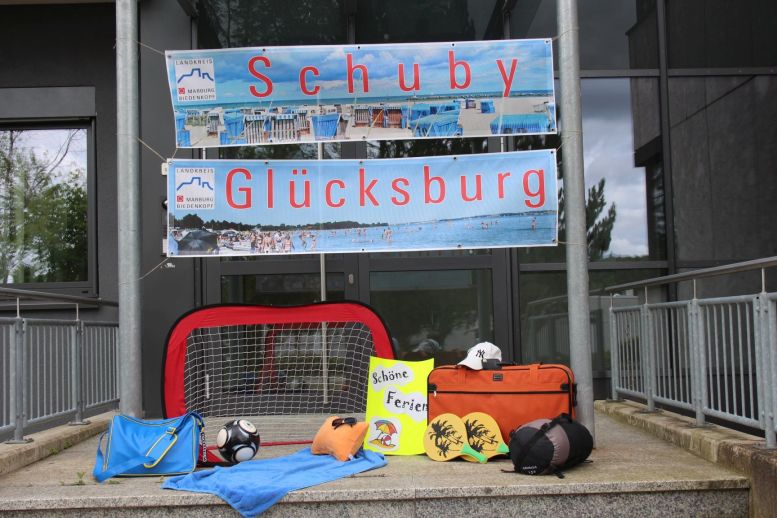 gepackte Koffer und Spielsachen und darüber Transparente vom Meer.