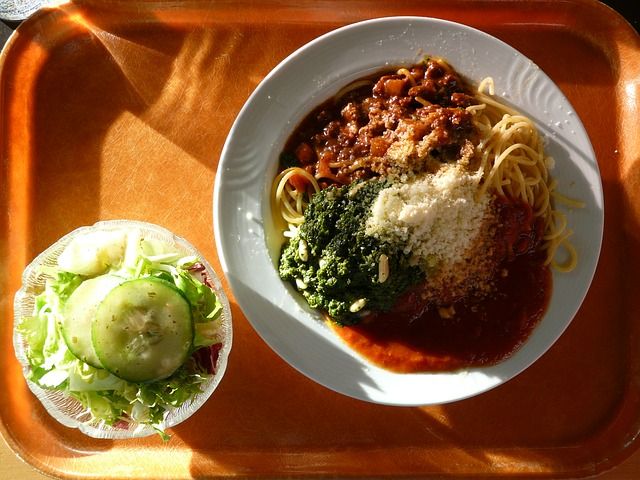 EIn Tablett mit Spaghetti mit Soße und ein Schälchen Salat