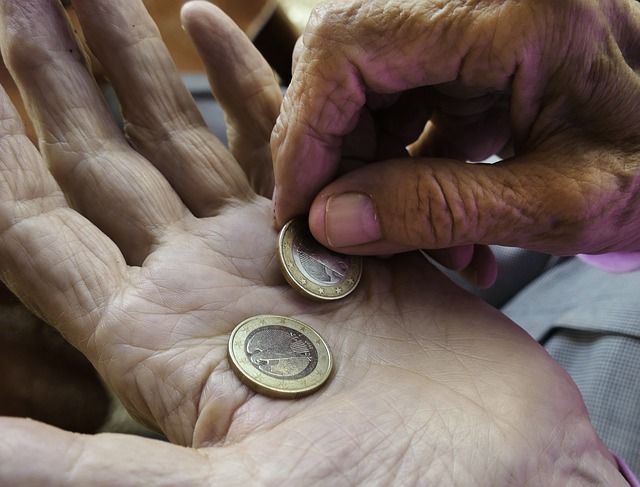 2 Hände einer alten Person die 2 Euro zählen.
