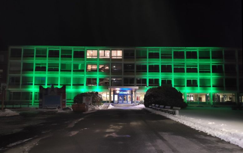 Schulgebäude, komplett grün angestrahlt