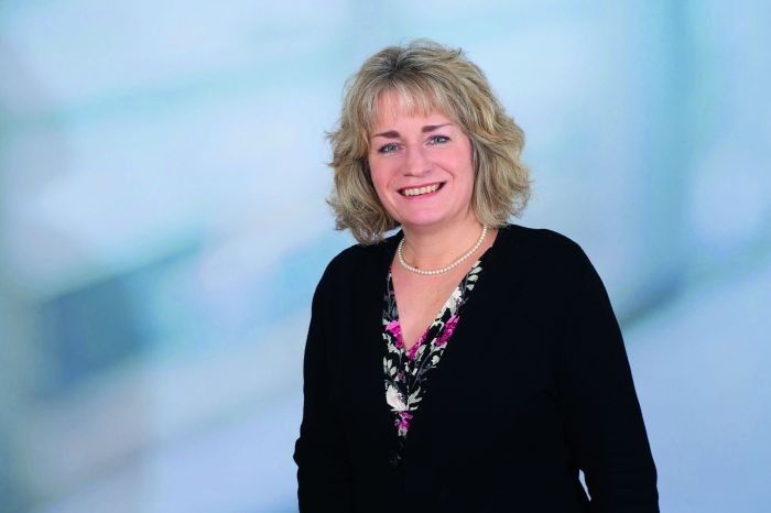 Aschblonde Frau mittleren Alters vor blauem Hintergrund