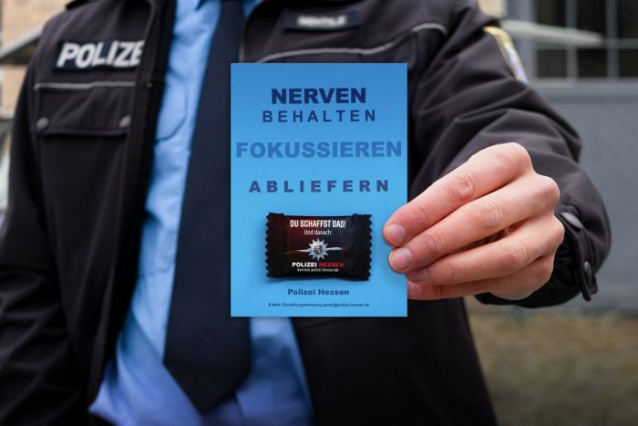 Polizist hält Mottokarte mit Traubenzucker in die Kamera.
