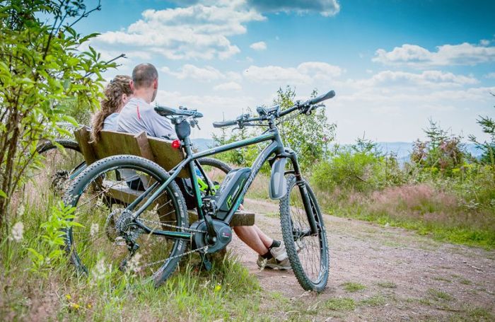 2 Leute auf einer Bank. E-Bikes daneben.