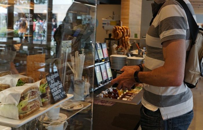 Mann in der Bäckerei. Geldbörse in der Hand.