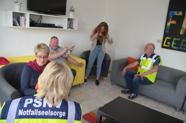 Menschen auf Sofas im Gespräch mit den Krisenmanagern