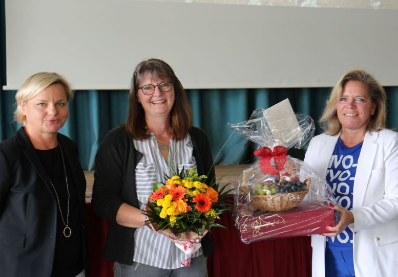 3 Frauen, die mittlere mit Blumenstrauß